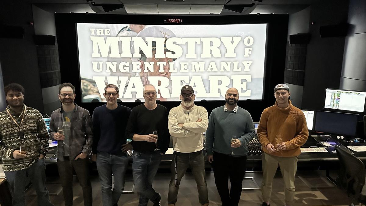 Alex with the sound team on the mix stage, the title of The Ministry of Ungentlemanly Warfare on the screen behind them